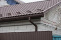 Long brown plastic drain pipe on a white brick wall of a house Royalty Free Stock Photo