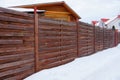 Long brown wooden fence on a rural street in white snow Royalty Free Stock Photo