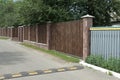 Long brown wooden fence on the streets near the gray asphalt road