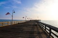 A long brown wooden pier with American flags flying from curved light posts and benches along the edge of the pier Royalty Free Stock Photo