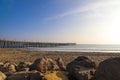 A long brown wooden pier with American flags flying on curved light posts with people walking and fishing on the pier Royalty Free Stock Photo