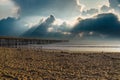 A long brown wooden pier with American flags flying on curved light posts with people walking and fishing on the pier Royalty Free Stock Photo