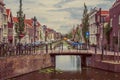 Long canal with small bridge, brick houses on its bank and cloudy day at Gouda.