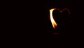 Long candle flame like heart shape in black background.