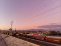 Long cargo train in Los Angeles and Transmission towers with purple sunset sky