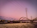 Long cargo train in Los Angeles under Transmission towers with purple sunset sky Royalty Free Stock Photo