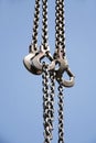 Long chains with hooks hanging vertically against blue sky