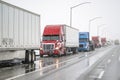 Long column of big rig semi trucks with semi trailers stands on the side of the highway due to a snow storm in the Shasta Lake