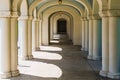 A long corridor in classical architectural style with many elegant columns and arches leading in perspective to a door Royalty Free Stock Photo