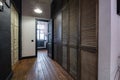 Long corridor in interior of entrance hall of modern apartments with doors, cabinets, shelves and a mirror