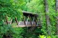 A long covered dark wood bridge over the Big Creek river surrounded by lush green lush green trees at Vickery Creek