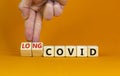 Long covid symbol. Doctor turnes wooden cubes and changes words `covid` to `long covid`. Beautiful orange background, copy spa