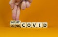 Long covid symbol. Doctor turnes wooden cubes and changes words `short covid` to `long covid`. Beautiful orange background, co