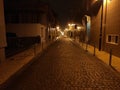 Long, dark cobbled Portuguese street at night in northern Portugal. Lit by yellow street lamps. Royalty Free Stock Photo