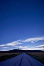 Long, desolate stretch of highway with tall power lines running parallel to it