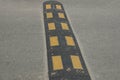 Long dirty black yellow speed bump on gray asphalt road