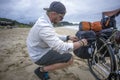 Long Distance Cyclist Prepares Panniers while on Beach Royalty Free Stock Photo