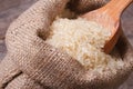 Long dry rice on wooden spoon macro in the sack