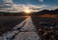 Scenic Desert Highway at Sunset with Dramatic Sunburst Over Mountains Royalty Free Stock Photo