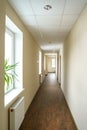 A long empty corridor in an office building. A new modern heating radiator on a white wall. Large double-glazed windows in a Royalty Free Stock Photo