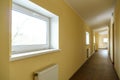 A long empty corridor in an office building. A new modern heating radiator on a white wall. Large double-glazed windows in a Royalty Free Stock Photo