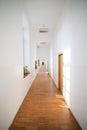 Long empty hallway inside an old building with white freshly painted walls and parquet floors Royalty Free Stock Photo