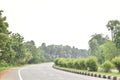 Long empty highway road turning right, palm tree on the roadside,and small trees on the divider, isolated with sky Royalty Free Stock Photo