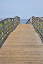 long and empty wooden foot path bridge over the marsh and water to the ocean beach Royalty Free Stock Photo