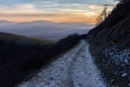 A long, endless mountain road with distant mountains in the background at dusk Royalty Free Stock Photo