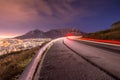 Long exposure of car driving around a bend with Table Mountain in the background in Cape Town as seen from Signal hill.