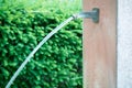 Long exposure of a closeup waterjet at a public fountain with low depth of field in front of a green hedge