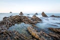 Long exposure fluffy ocean mists rush over tidal pool rocks at the beach Royalty Free Stock Photo
