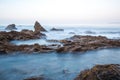 Long exposure fluffy ocean mists rush over tidal pool rocks at the beach Royalty Free Stock Photo