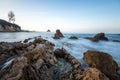 Long exposure fluffy ocean mists rush over tidal pool rocks at the beach Royalty Free Stock Photo