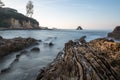 Long exposure fluffy ocean mists rush over tidal pool rocks at the beach Royalty Free Stock Photo