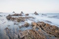 Long exposure fluffy ocean mists rush over tidal pool rocks at the beach Royalty Free Stock Photo