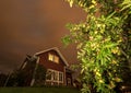 Long exposure night photo of traditional red wooden swedish house and dark heavy clouds with apple tree Royalty Free Stock Photo