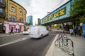 Long exposure of the painted Camden Lock bridge across Camden High Street with a blurred red white van passing underneath