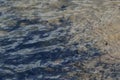 A long exposure photo creating soft water ripples. Overhead view with changing colors where the river water meets the sandy shore. Royalty Free Stock Photo