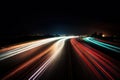 a long exposure photo of a highway at night with light streaks on the road and buildings in the distance with lights on the side Royalty Free Stock Photo