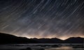 Long exposure photography capturing stars trailing across the cosmos. Streaks of white against a deep