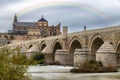 Long exposure photography of Mosque-Cathedral and the Roman Bridge in Cordoba with cloudy sky and a rainbow, Andalusia, Spain