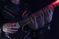 Long Exposure picture of a man wearing a leather jacket playing a black and yellow electric guitar at indoor iluminated with red a Royalty Free Stock Photo