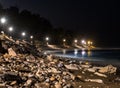 Long exposure of red lantern in the foreground on stones on the beach of night Marbella, with small lights emulating the flames