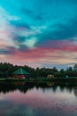 Long exposure scenic view of small red house on the bank of still pond Royalty Free Stock Photo