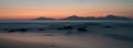 A long exposure of the sea at golden hour, as the sun sets behind a mountain.