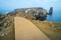 Long exposure seascape of the cliffs of Papoa island and wooden bridge way in Carvoeiro cape in a foggy morning, Atlantic coast, Royalty Free Stock Photo