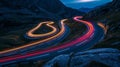 A long exposure shot capturing the light trails of multiple cars speeding along the winding mountain road Royalty Free Stock Photo