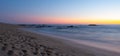 Long exposure shot over beach at dusk with milky ocean and smooth blue orange gradient sky