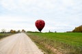 Long exposure shot of a road with a person passing by a red hot air balloon ready to take off Royalty Free Stock Photo